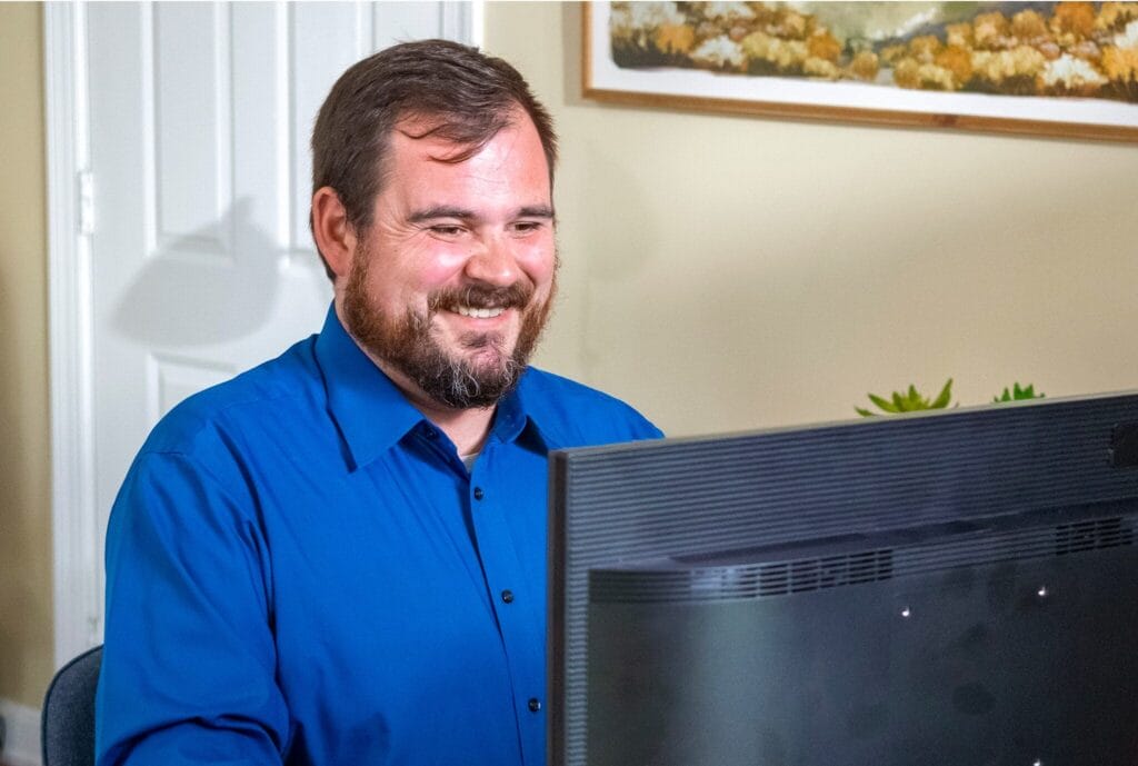 Man with blue shirt in front of computer