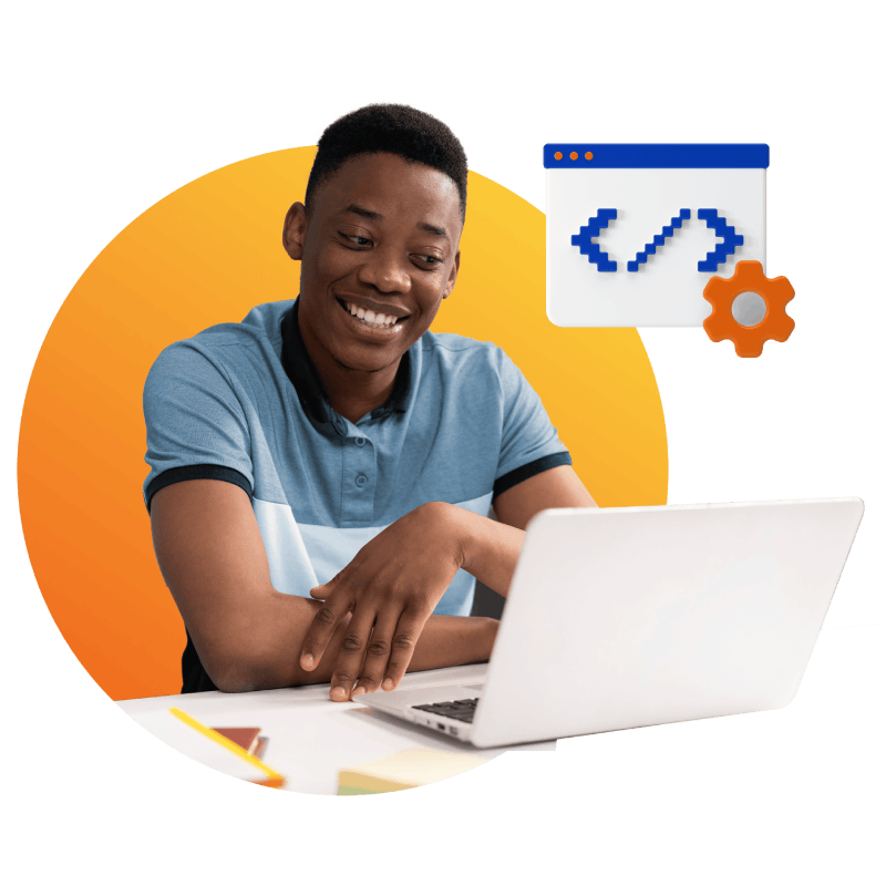 A young man seated at a desk, working on a laptop and a computer, focused on his tasks.