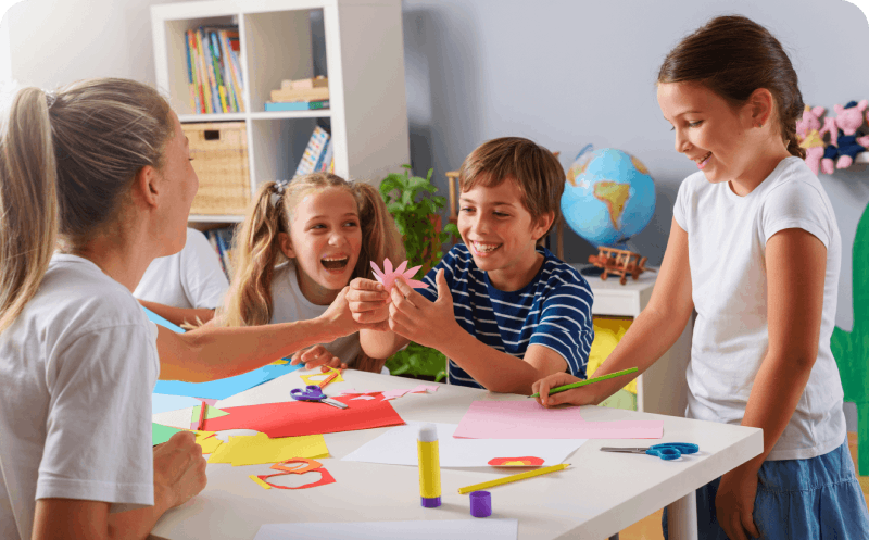 A group of children and adults engaged in creative paper crafts at a table, showcasing their artistic projects and collaboration.