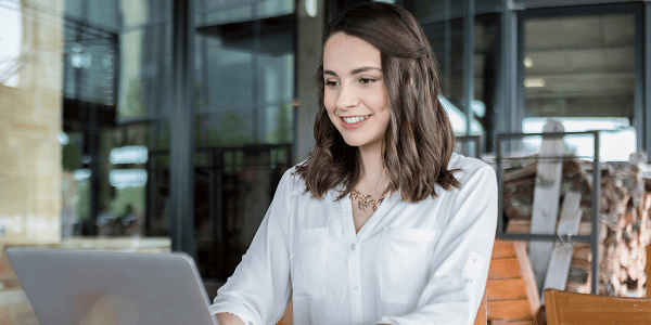 A woman working at a table with a laptop, appearing engaged and thoughtful in a comfortable environment.
